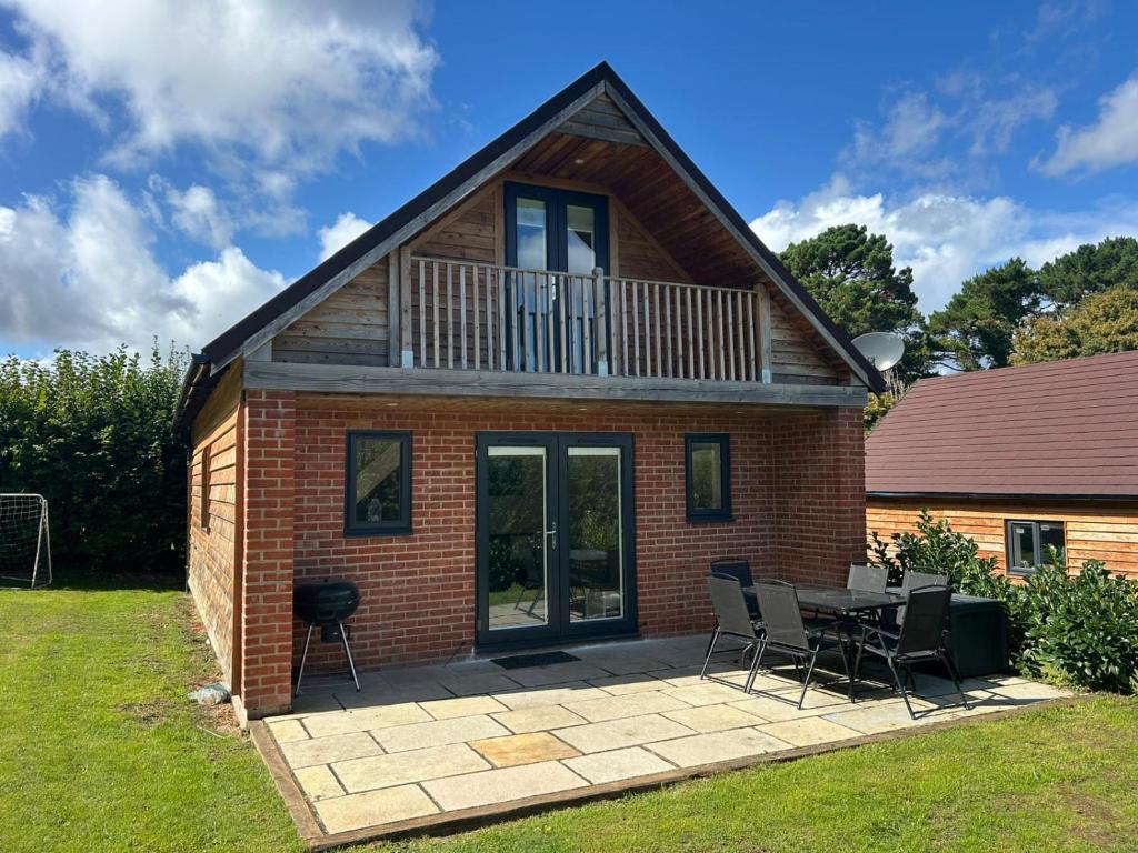 a house with a patio and a table and chairs at Beechen Lodges in Bishops Waltham