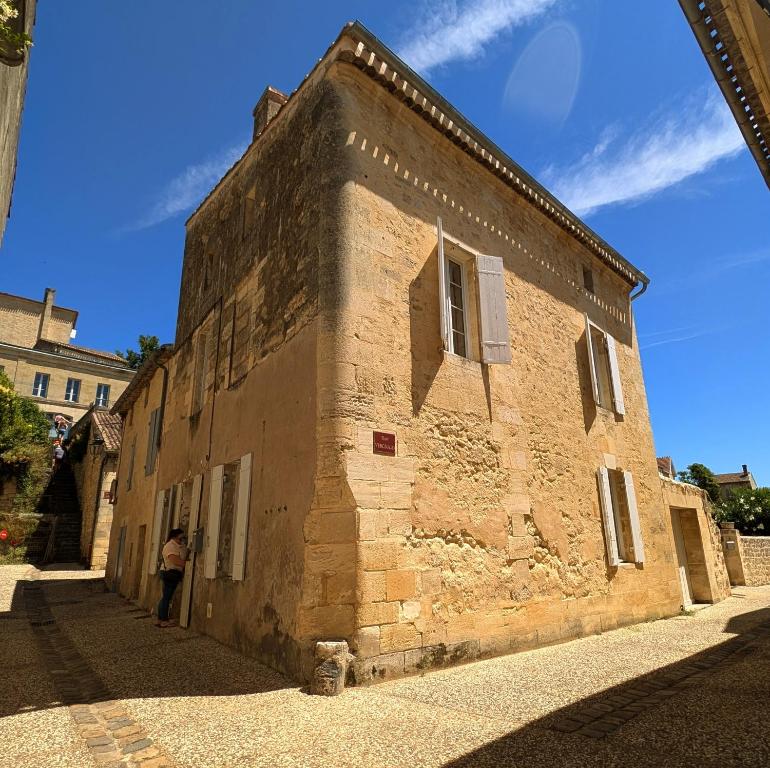 eine Person, die vor einem Backsteingebäude steht in der Unterkunft La Maison du Clocher in Saint-Émilion