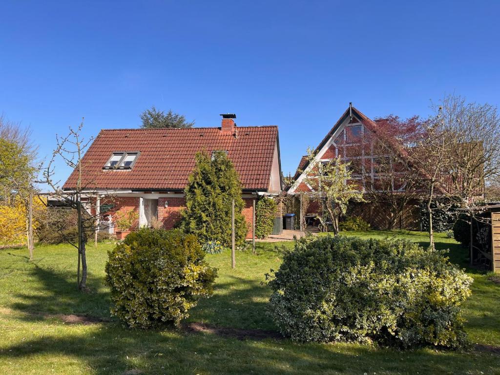 une maison avec un toit rouge et quelques buissons dans l'établissement Ferienwohnungen Altes Land I Jork-Borstel, à Jork
