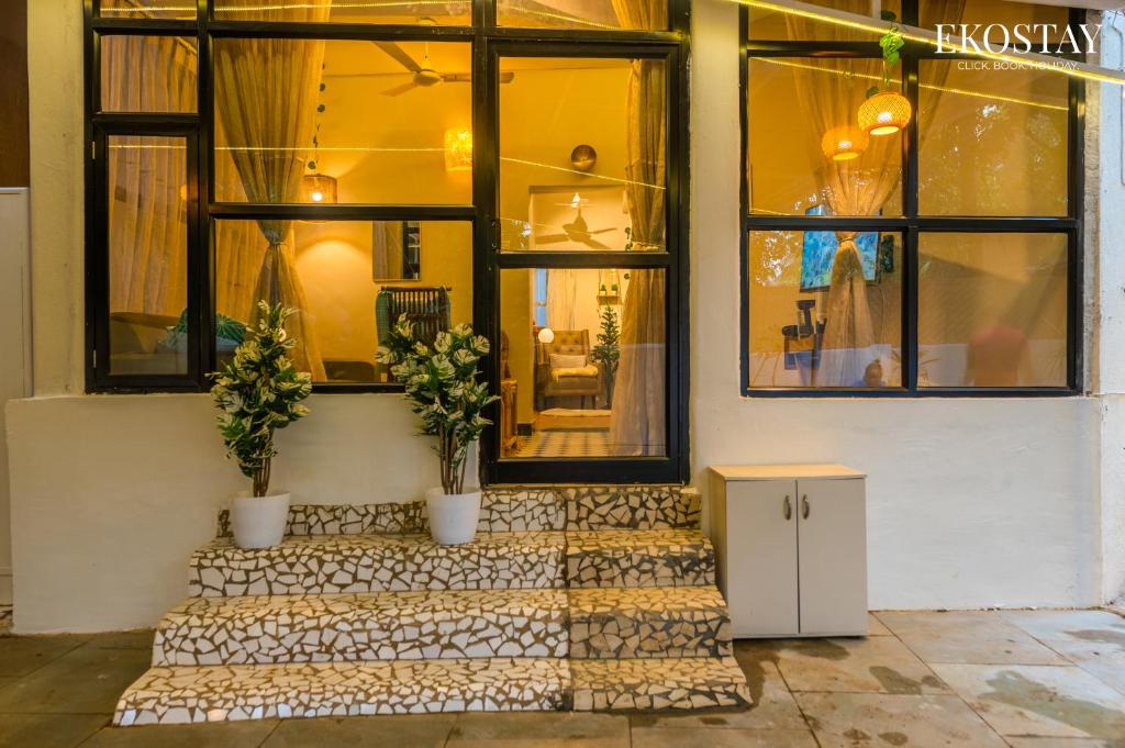a store front with two potted plants on the stairs at EKOSTAY - Copacabana Villa in North goa