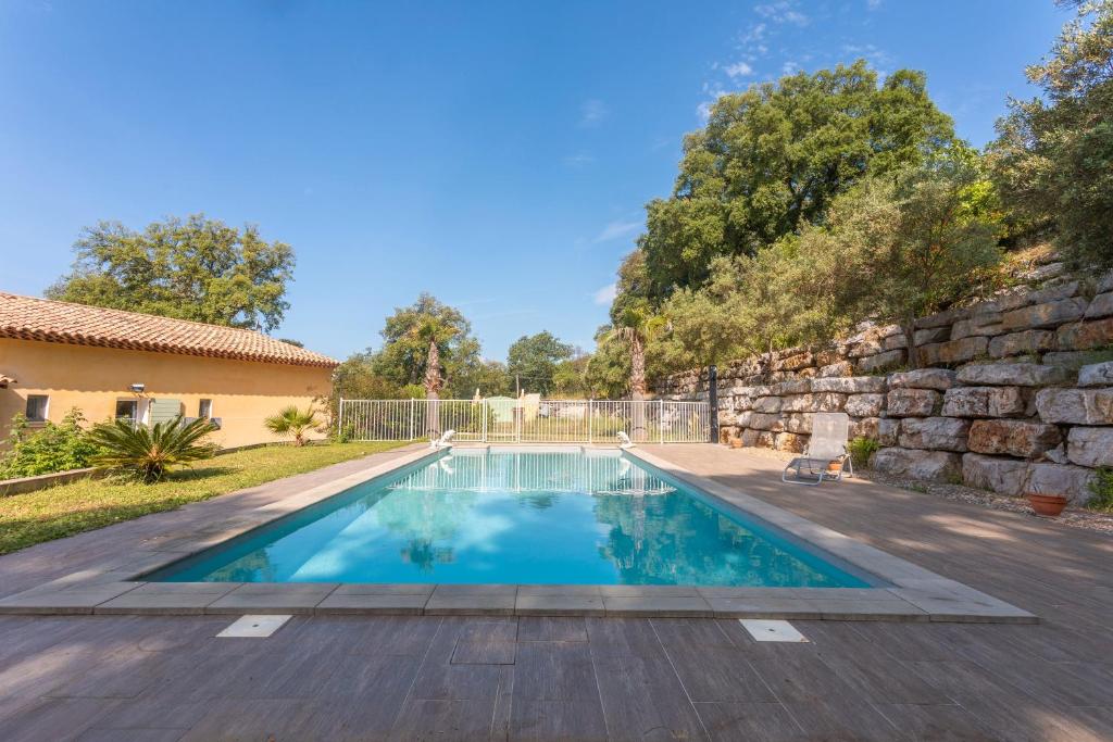 una piscina en un patio trasero con una pared de piedra en Maison d'hôtes Collobrières, en Collobrières