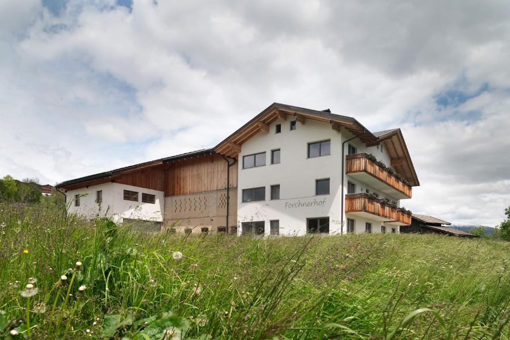 a building on top of a hill with a field at Forchnerhof Apt Ploseblick in Maranza