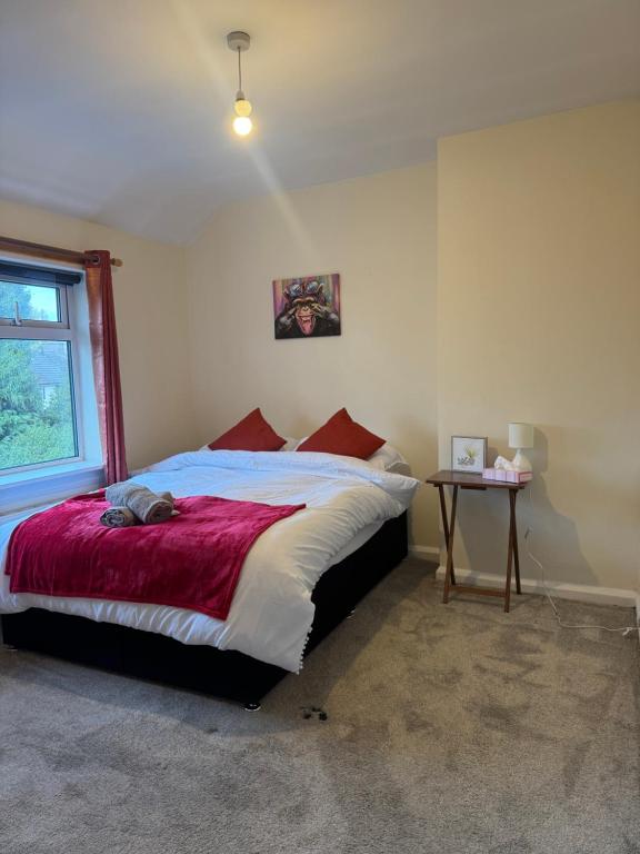 a bedroom with a bed with a red blanket and a table at Cosy 3 Bedroom in Birmingham in Birmingham