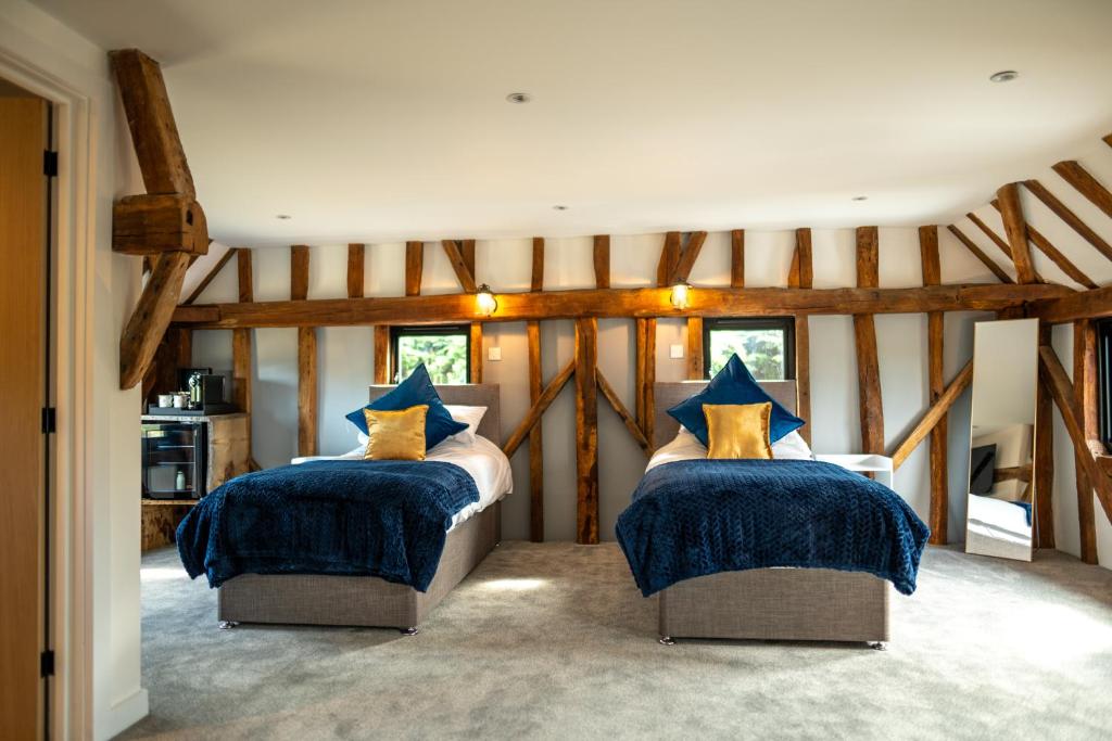a bedroom with two beds with blue and yellow pillows at The Barn at Chart Hills in Biddenden