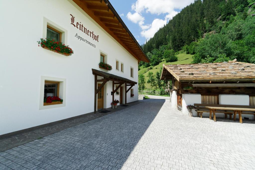 ein Gebäude mit einer Bank neben einem Gebäude mit Bergen in der Unterkunft Leitnerhof in Ratschings