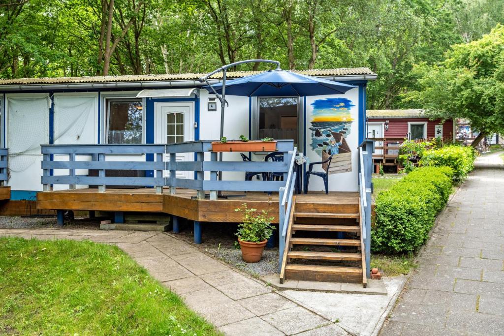 a blue and white trailer with a table and an umbrella at Bungalow Kay, Bgl 4 in Dranske