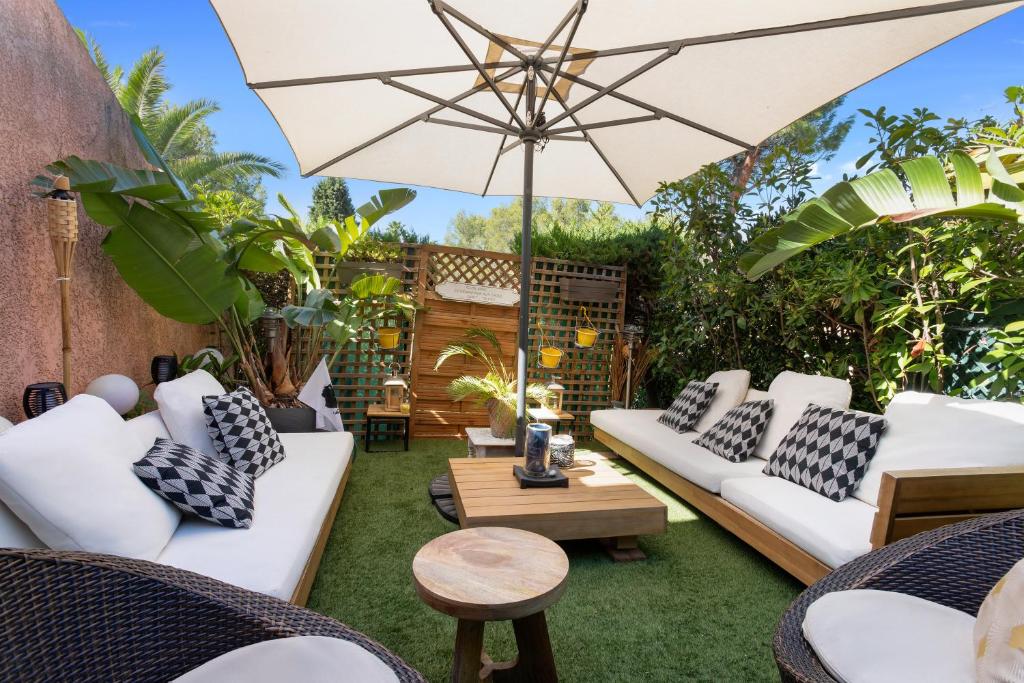 eine Außenterrasse mit weißen Sofas und einem Sonnenschirm in der Unterkunft Domaine de la Corniche in Saint-Raphaël