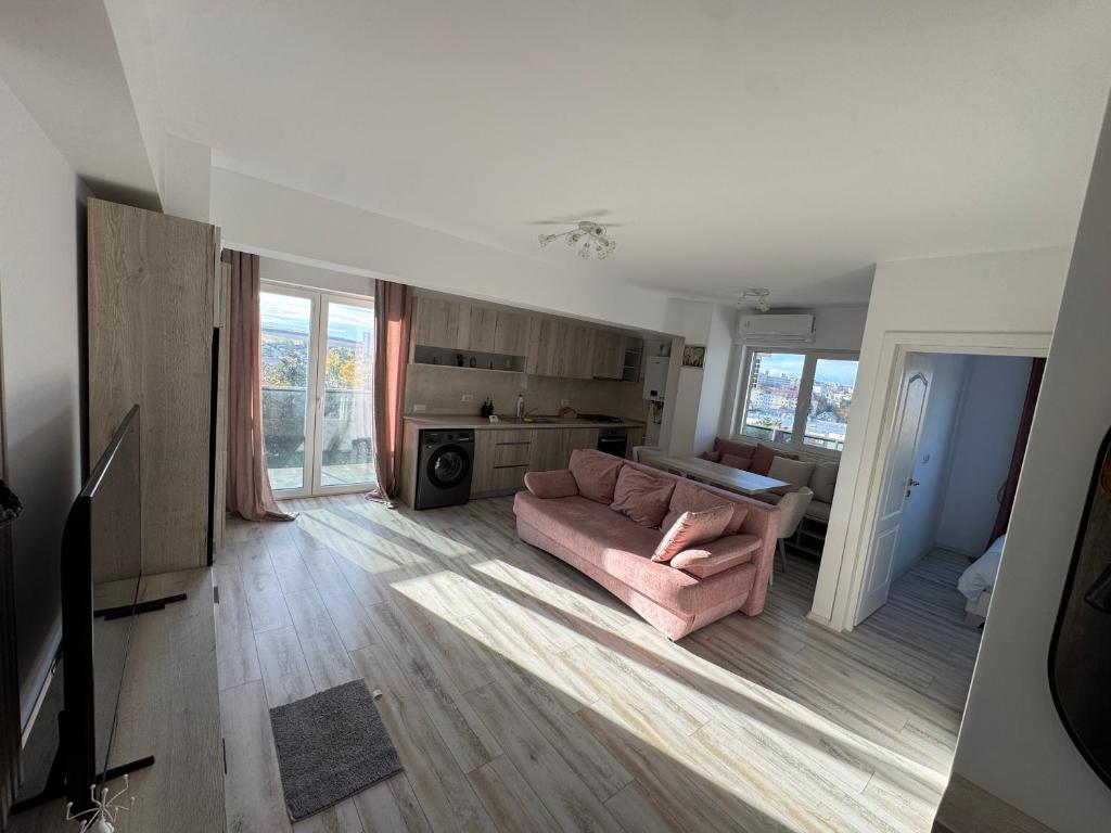 ein Wohnzimmer mit einem rosa Sofa und einer Küche in der Unterkunft Staywell University with underground parking in Suceava