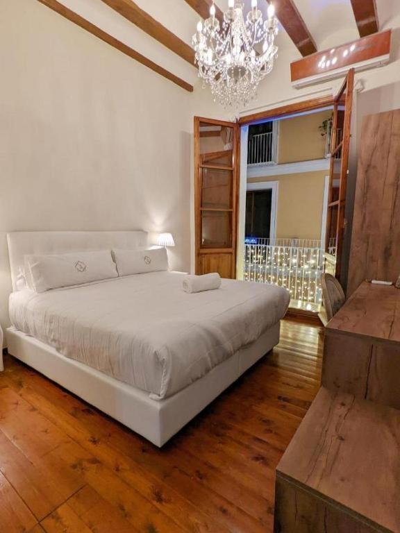 a bedroom with a white bed and a chandelier at Hotel Catalina Suites in Valencia