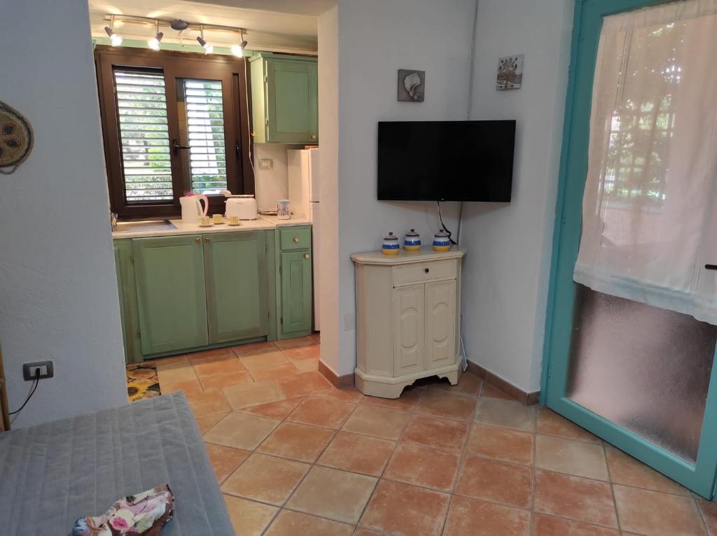 a kitchen with green cabinets and a flat screen tv at Villetta agli ulivi in San Teodoro