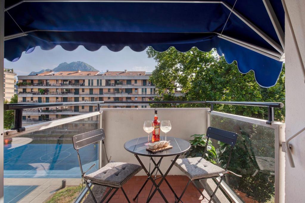 a table with a bottle and two chairs on a balcony at Lake Como Design Home in Lecco