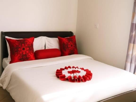 un lit avec des oreillers rouges et blancs dessus dans l'établissement Cozy Haven kitengela, à MakandaraHousing Estate