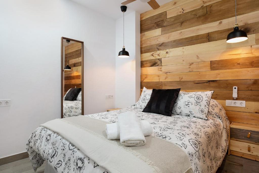 ein Schlafzimmer mit einem Bett mit einer Holzwand in der Unterkunft Apartamento El Músico in Barbate