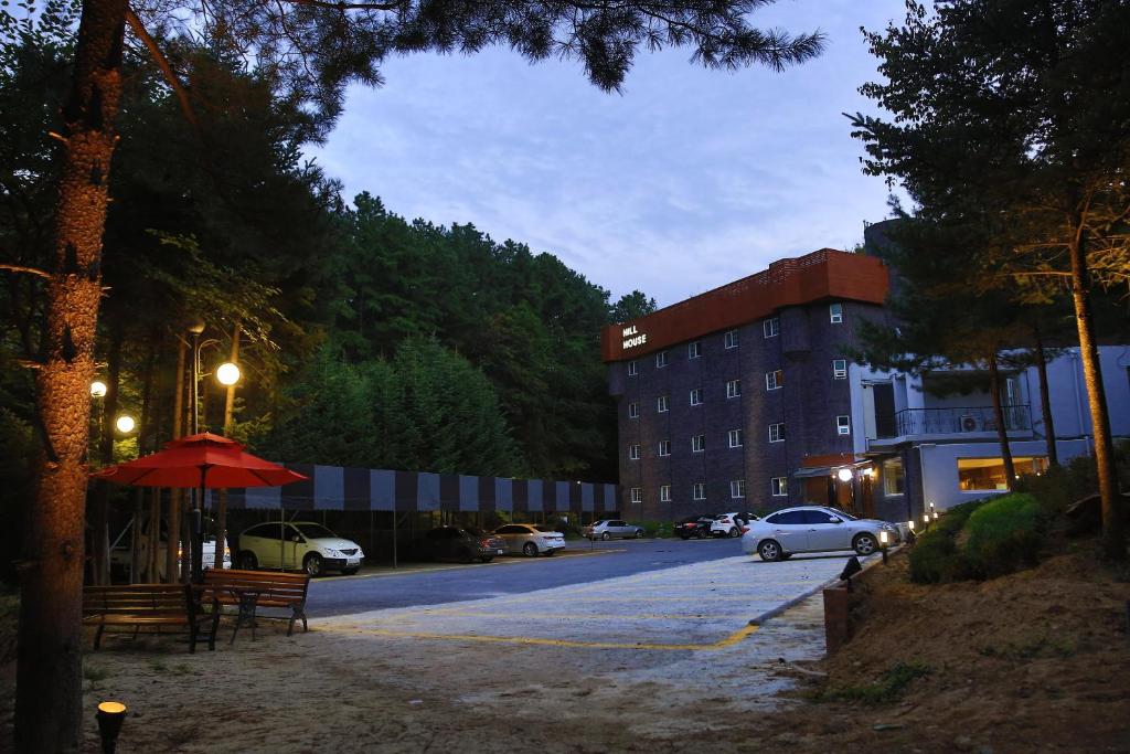 a street with a building and cars parked in a parking lot at Hill House Hotel in Pocheon