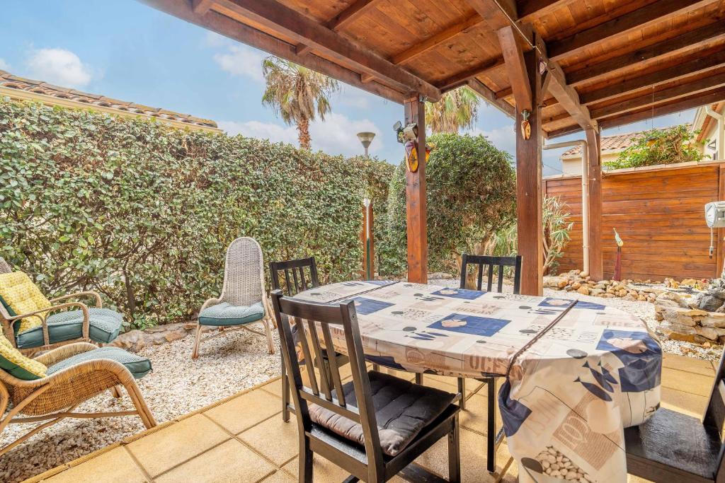 une table et des chaises en bois sur une terrasse dans l'établissement Appartement Avec Jardin et piscine, à Narbonne