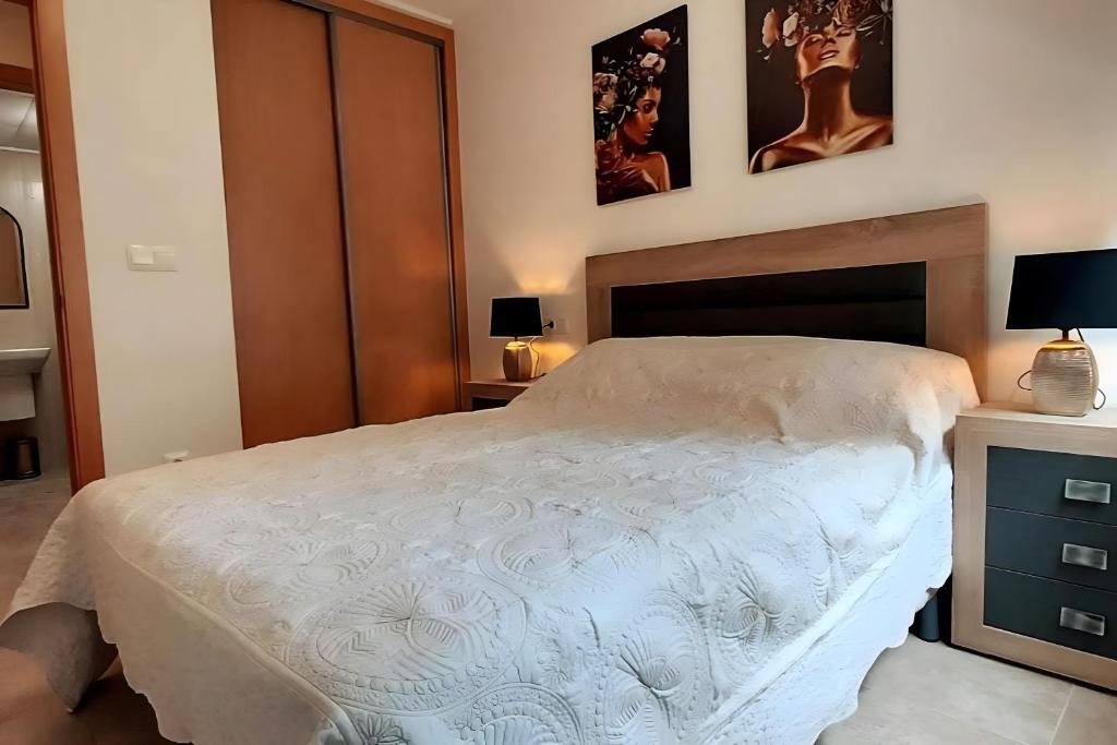 Un dormitorio con una cama y dos cuadros en la pared. en Antina 12 en Santa Pola, en Santa Pola