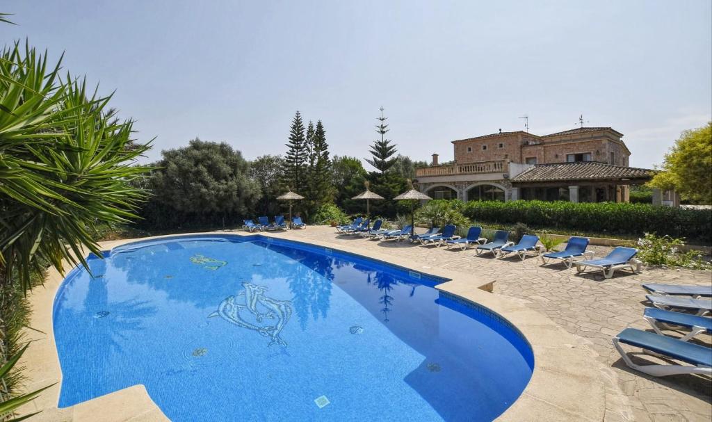 una grande piscina blu con sedie e un edificio di Na Pont a Campos