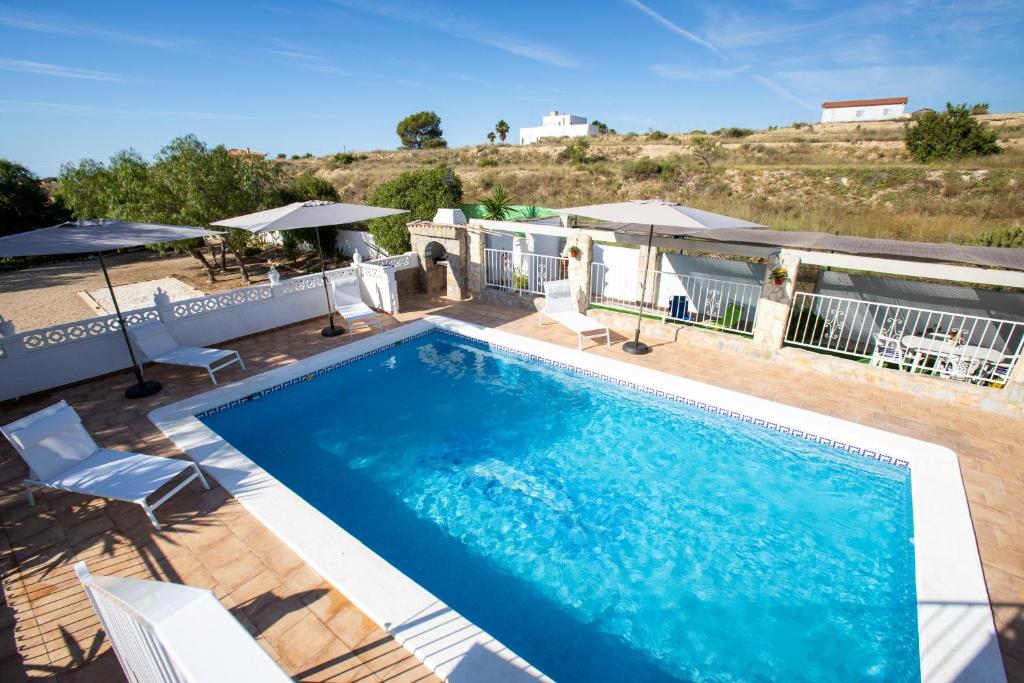a swimming pool with chairs and umbrellas on a patio at La Casita in San Vicente del Raspeig