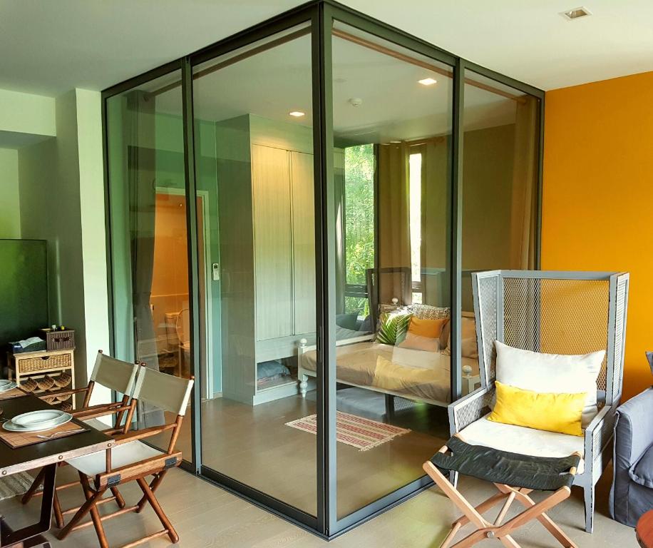 a living room with glass walls and a chair at The Valley Escape สองห้องนอน สวย สงบ สบาย in Phayayen
