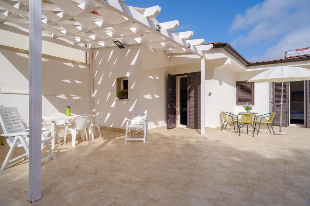 a patio with chairs and a table and an umbrella at Villa Namastè in Porto Cesareo