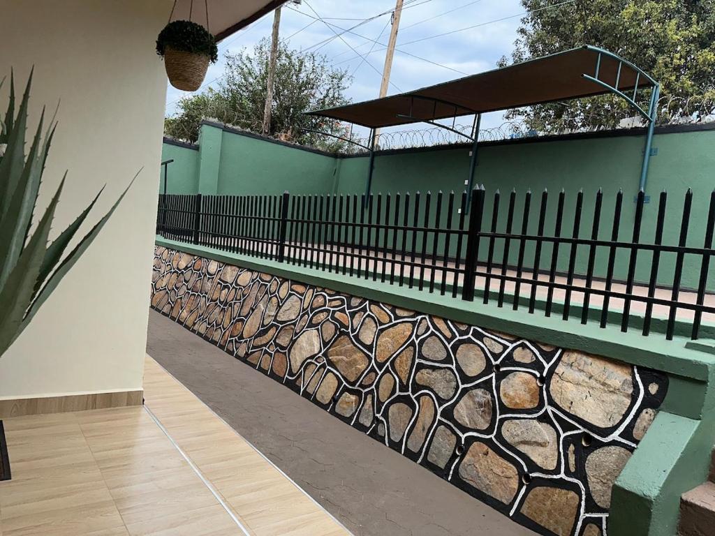 a fence next to a wall with rocks at The K Residence in Kampala