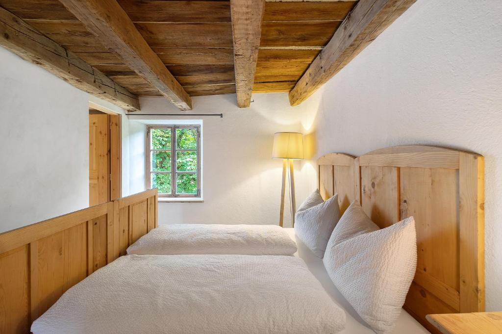 two beds in a bedroom with wooden ceilings at Ansitz Baumannhof Apt Mitte in Falzes
