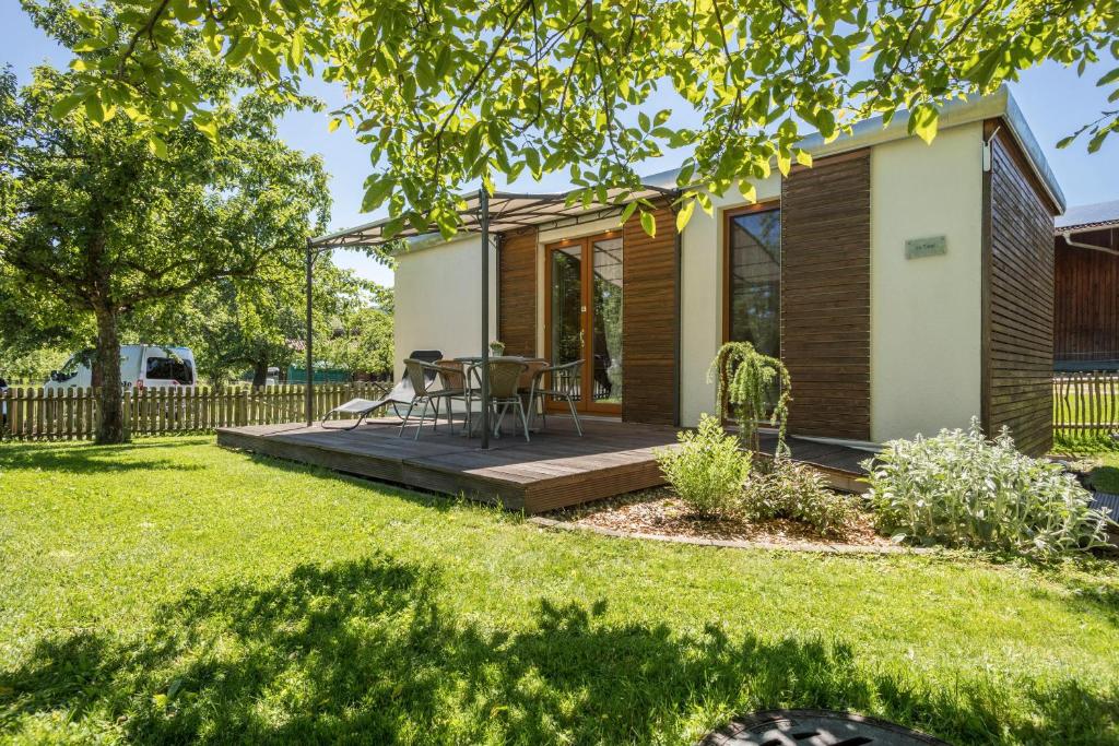Una pequeña casa con una terraza de madera en un patio. en Ferienhaus Im Tobel, en Deggenhausertal