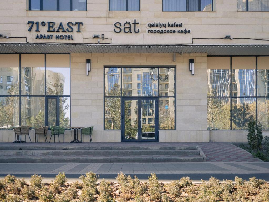 a building with tables and chairs in front of it at 71 East Apart Hotel in Astana