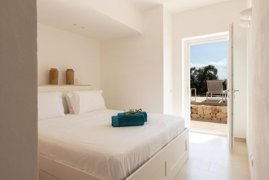 - une chambre blanche avec un lit doté d'un sac bleu dans l'établissement Villa Panitria, à Ostuni
