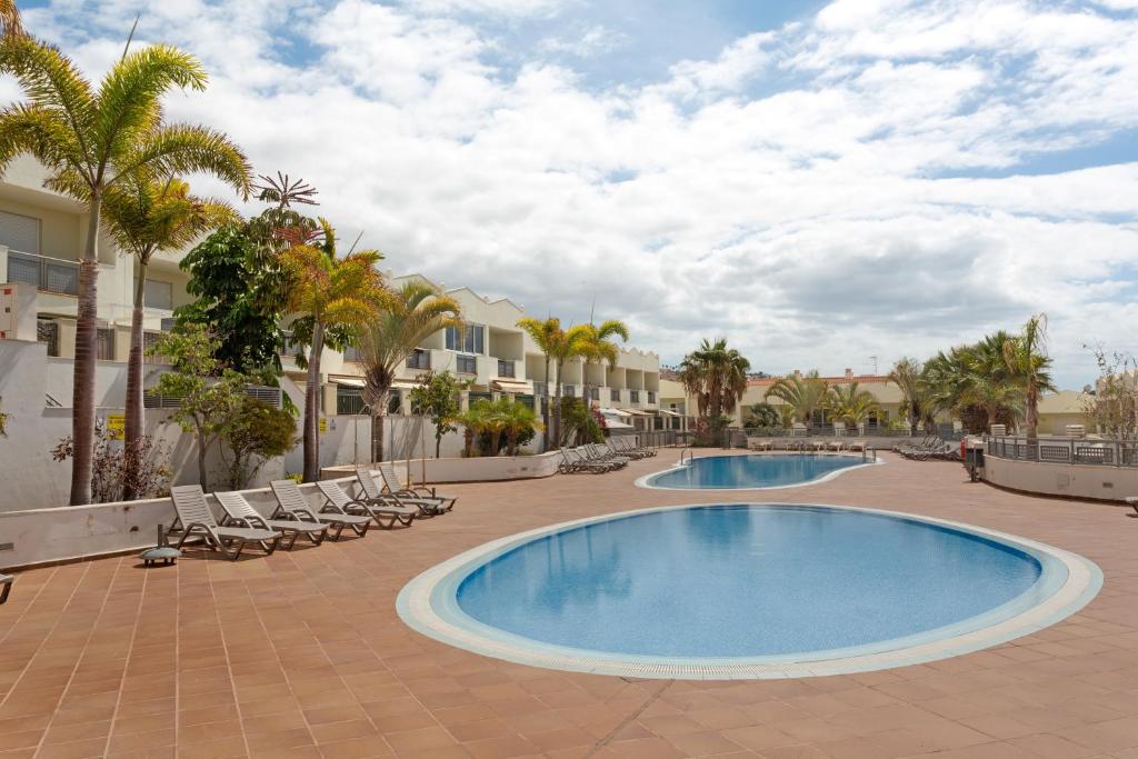 a resort swimming pool with chairs and palm trees at Obsidian Olivino Miraverde in Adeje