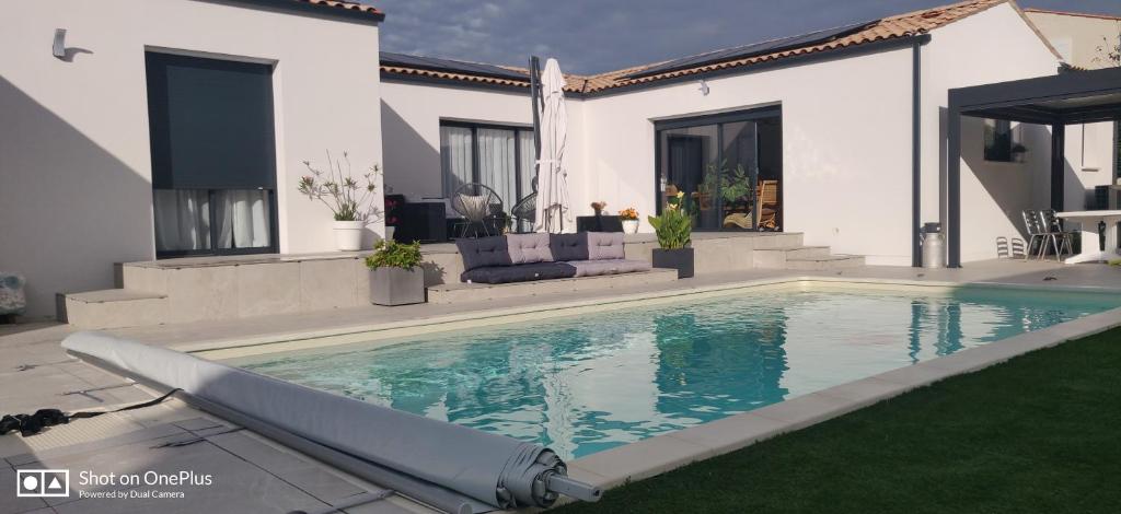 a swimming pool in front of a house at Maison 2 couchages in Aigrefeuille-dʼAunis
