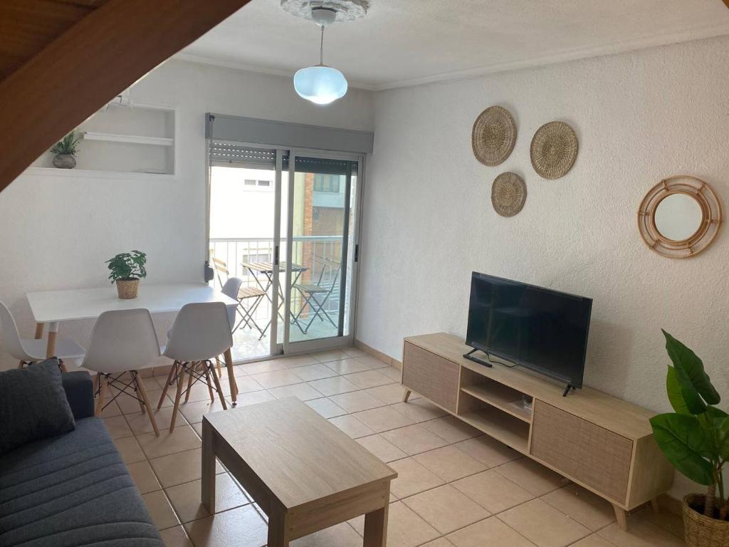 ein Wohnzimmer mit einer Couch, einem Fernseher und einem Tisch in der Unterkunft Piso El Grao in Grao de Castellón