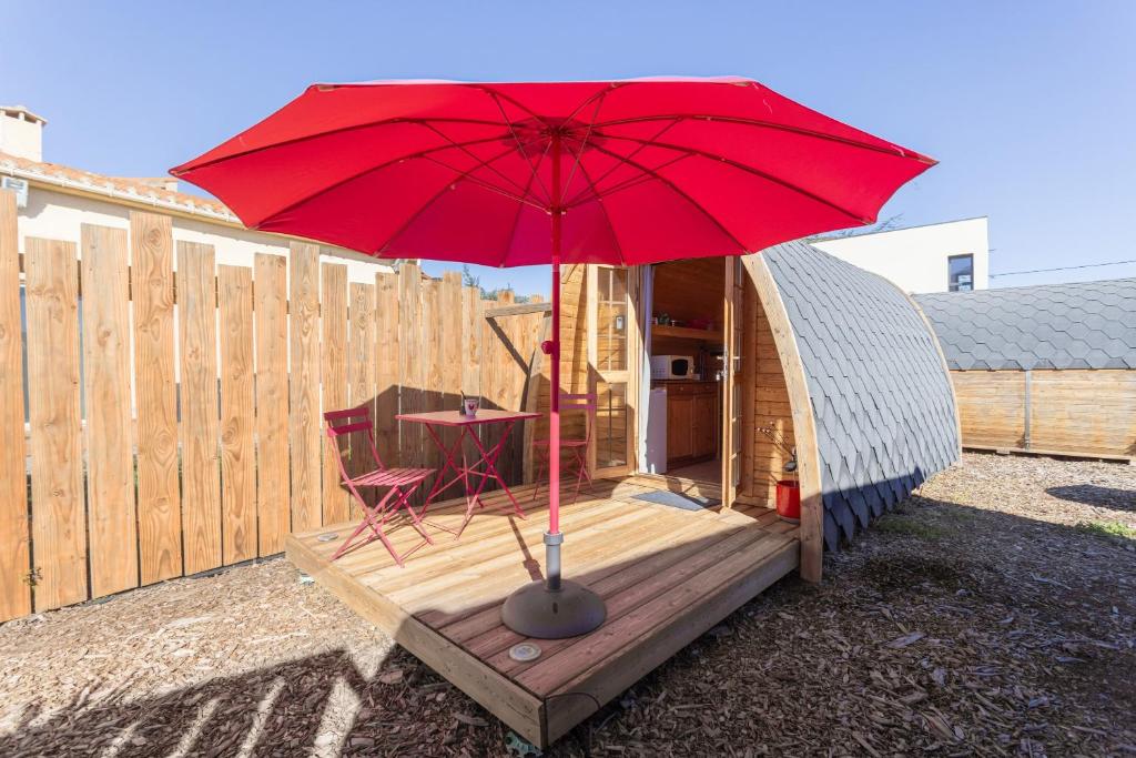 a red umbrella on a deck with a table and a chair at Pink Pod in Saint-André