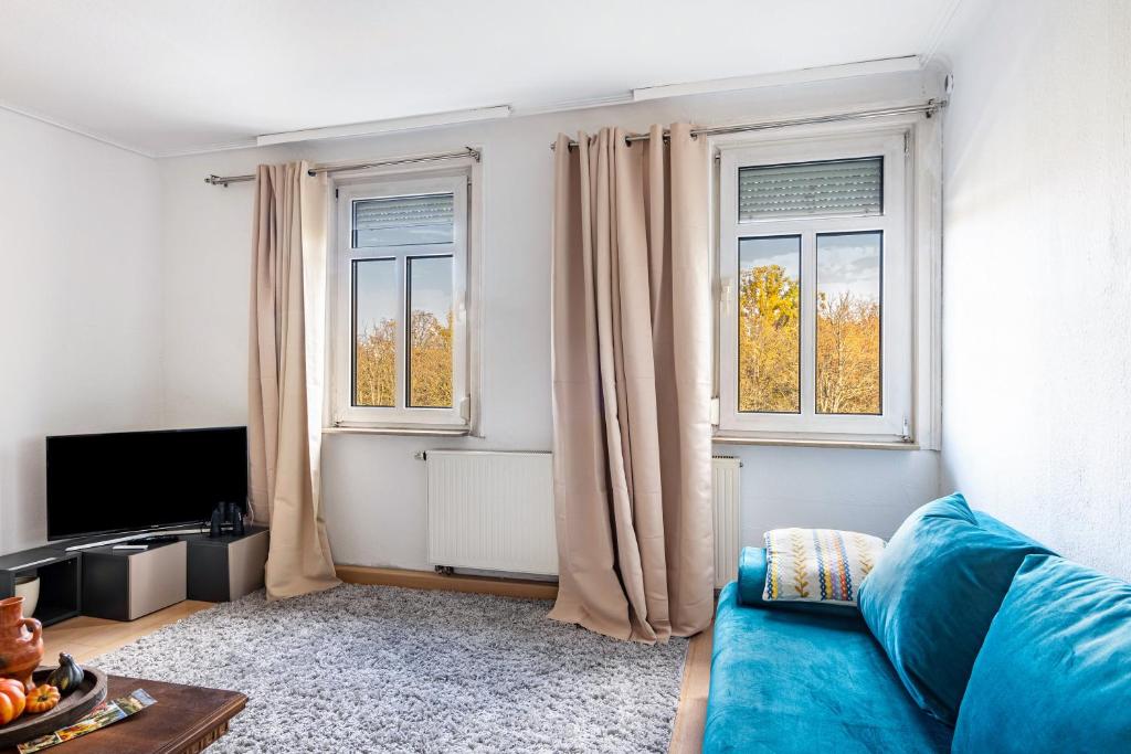 a living room with a blue couch and two windows at Malachit in Ludwigsburg