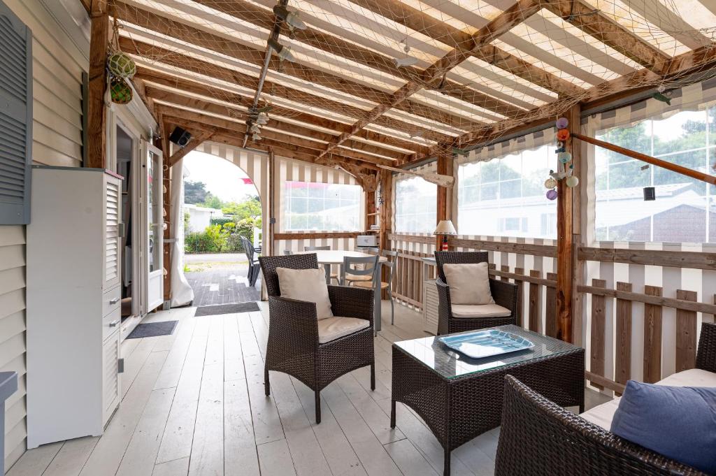 - une véranda avec des chaises et une table dans l'établissement Mobilhome 6 pers - Piscine, à Saint-Gildas-de-Rhuys