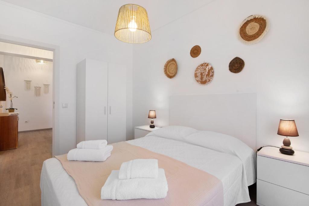 a white bedroom with a bed and two towels at Justo's House in Faro