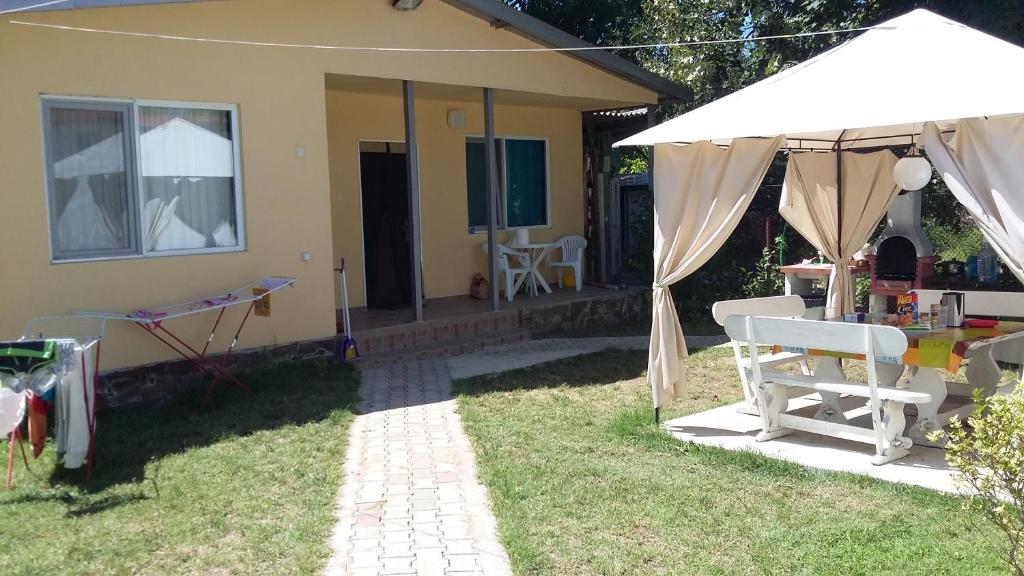 a house with a table and a white umbrella at Bungalows St. Nicola in Ahtopol