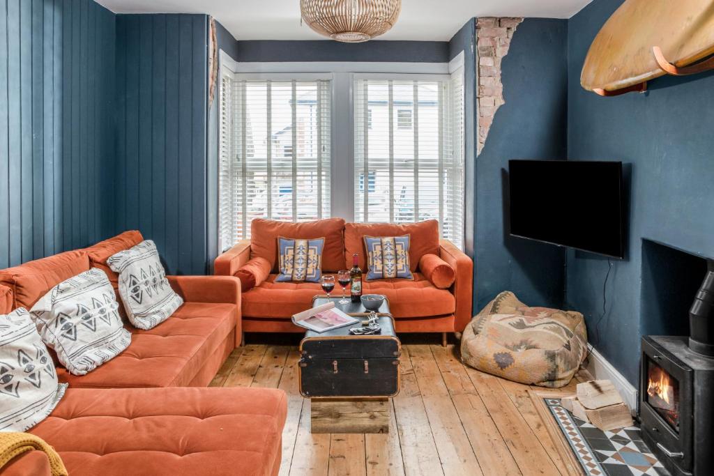 een woonkamer met oranje banken en een tv bij The Bunker House in Newquay