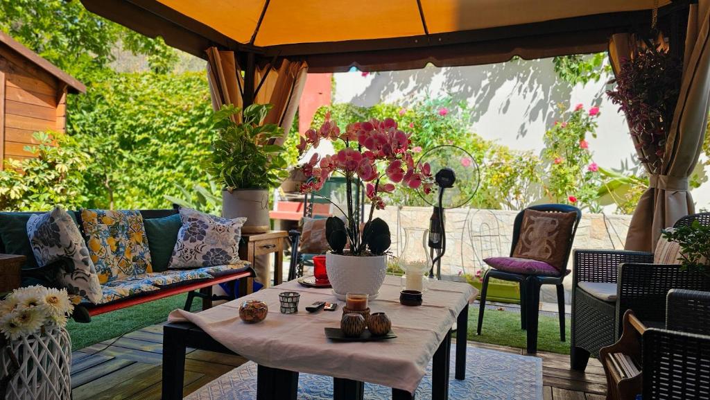 a patio with a table with flowers on it at Lux Energy Room and Garden in Olbia