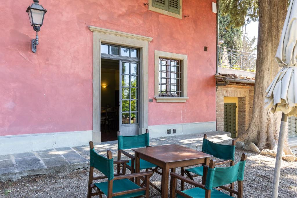 a table and chairs in front of a pink building at Fattoria la Gigliola - Il Frantoio in Montespertoli