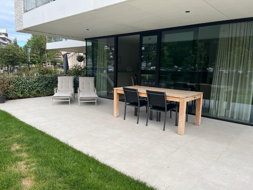 een houten tafel en stoelen op een terras bij Logies La Parmentière in De Panne