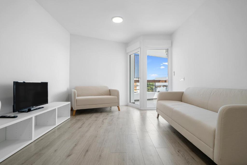 a white living room with a couch and a tv at Formentor 863 in Salou