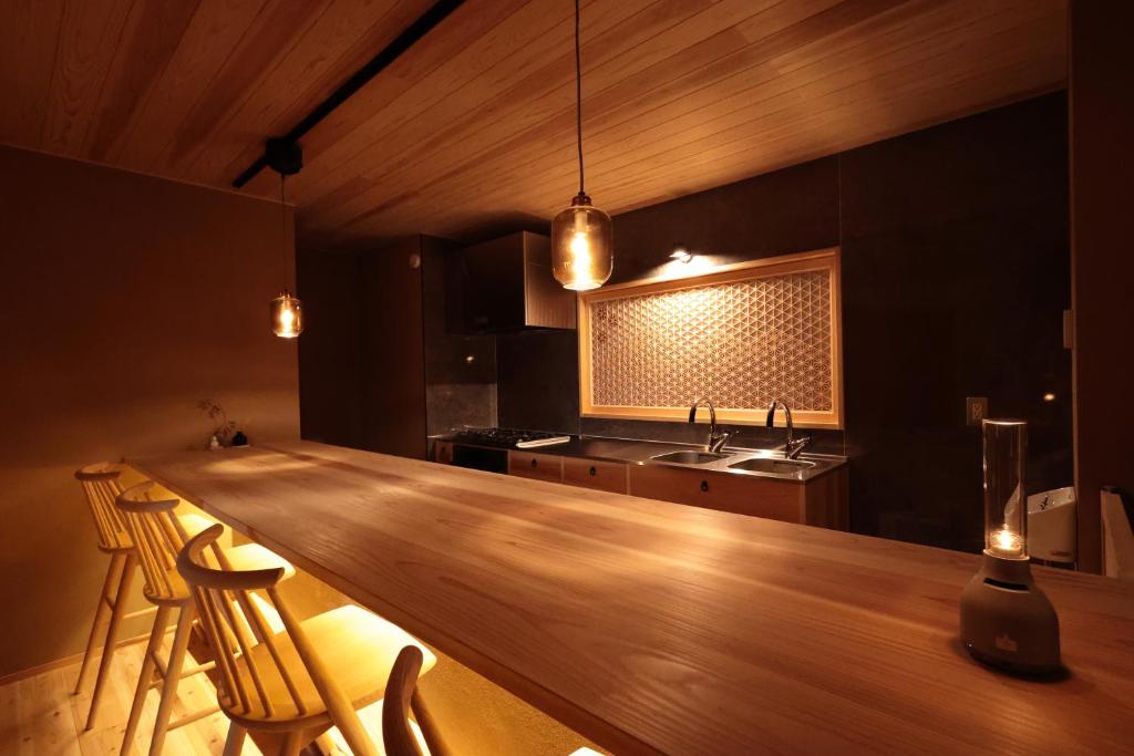una cocina con una barra de madera con sillas y un fregadero en Sion Hotel, en Hatsukaichi