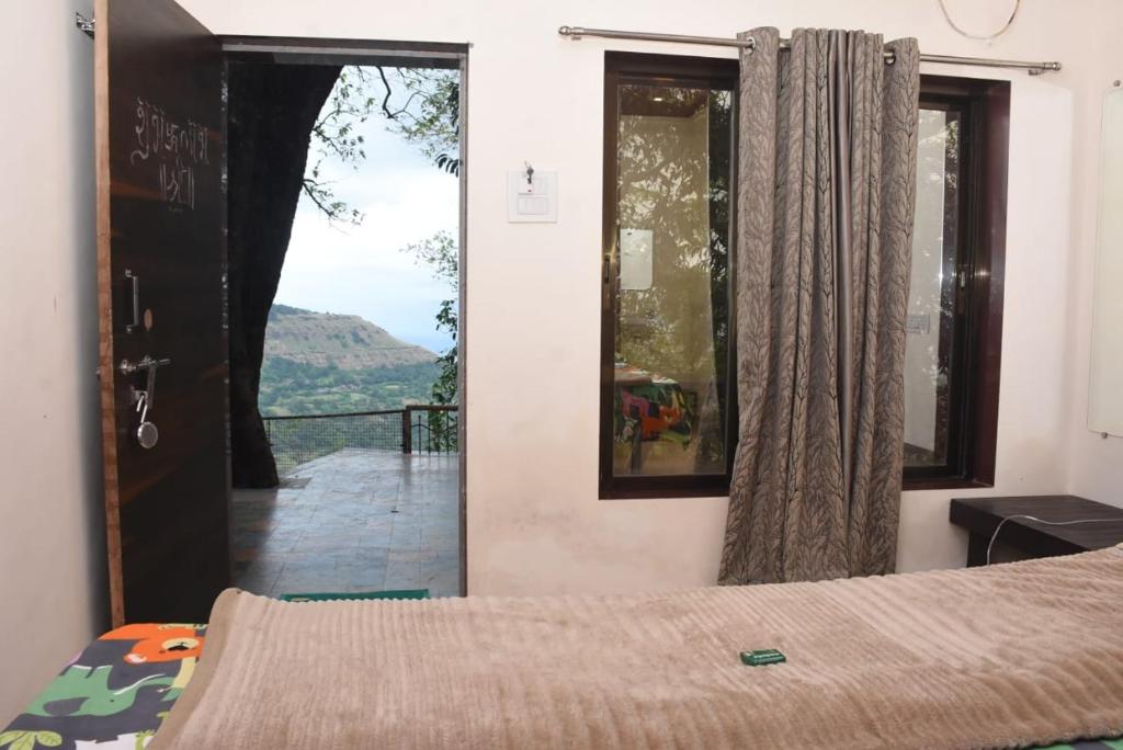 a bedroom with a bed and a window with a view at The Grand Bagicha And Baba House in Matheran