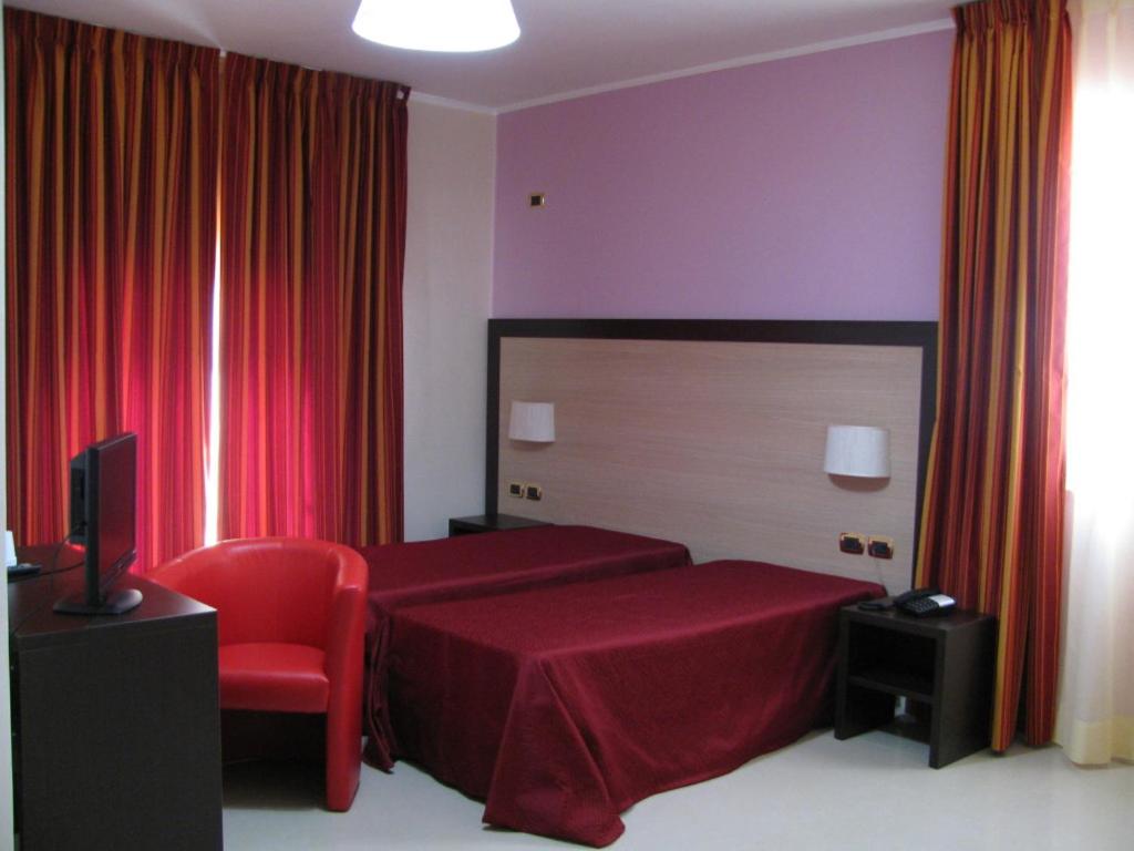 a bedroom with a red bed and a red chair at Albergo Roma in San Ferdinando di Puglia
