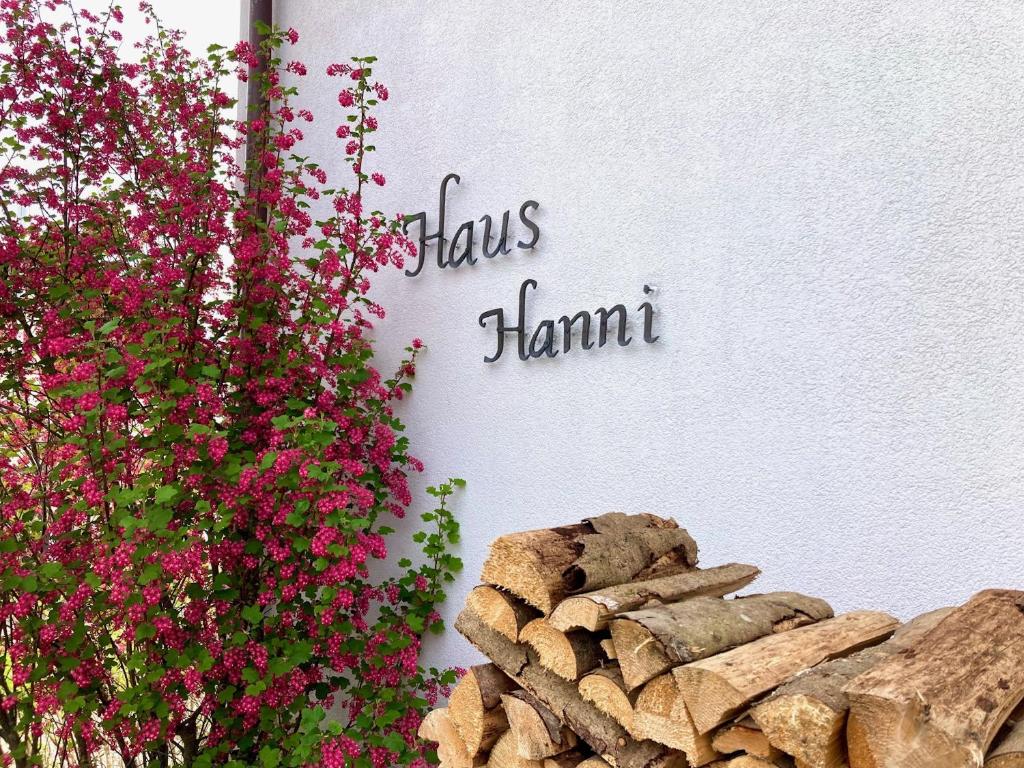 ヘーヘンシュヴァントにあるHaus Hanniの花が飾られた壁と「flux hamant」と書かれた看板