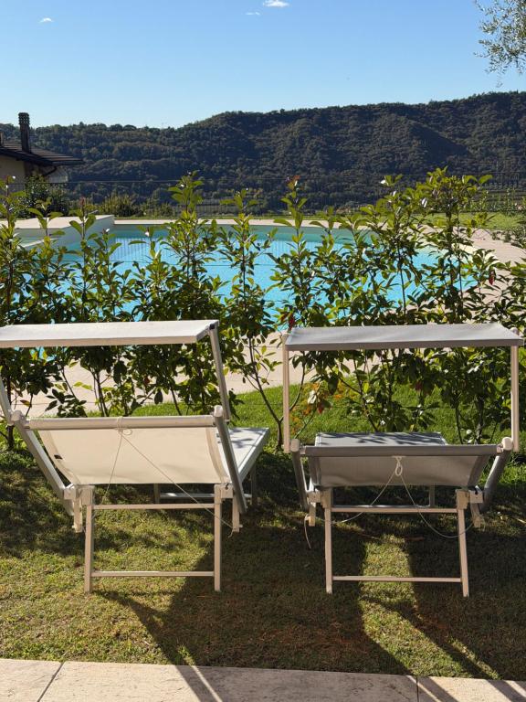 two chairs sitting on the grass near a body of water at Villa La Dolce Vita in Costermano sul Garda