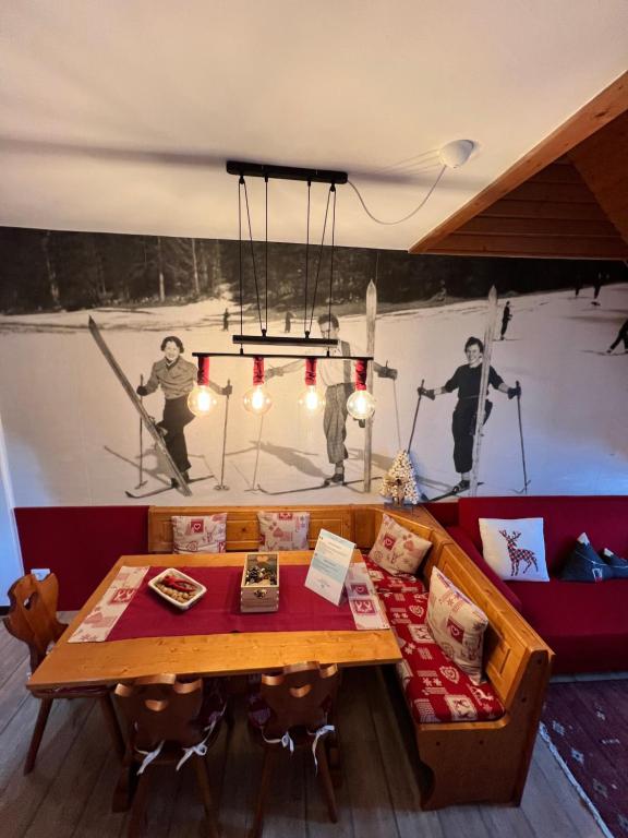 a room with a table and a painting of skiers at Mandi Mandi a Tarvisio in Tarvisio