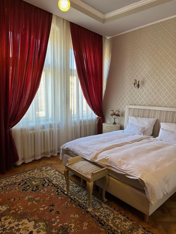 a bedroom with a large bed with red curtains at Guest House Anna Caffe in Bezdan