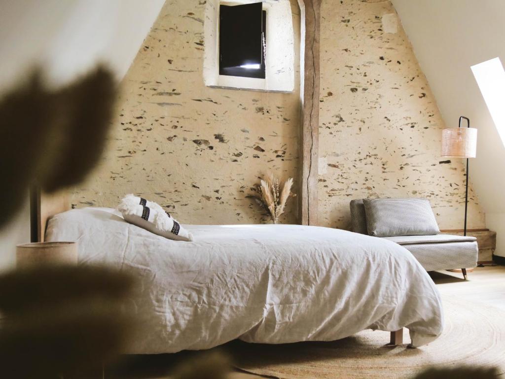 a bedroom with a bed and a wall with a window at Manoir Du Moulinet in Château-Gontier